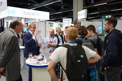 Menschen unterhalten sich an Messestand der Strategischen Partnerschaft Sensorik